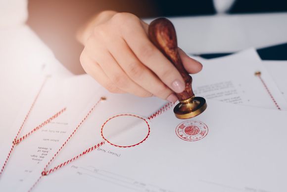 A person is stamping a document with a wax seal.