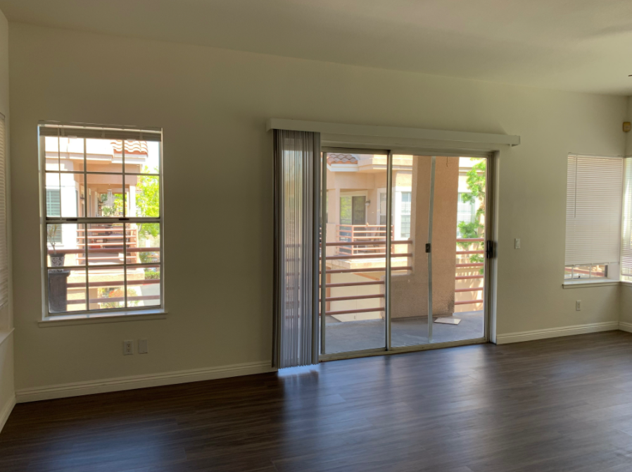 an empty living room with a sliding glass door leading to a balcony .