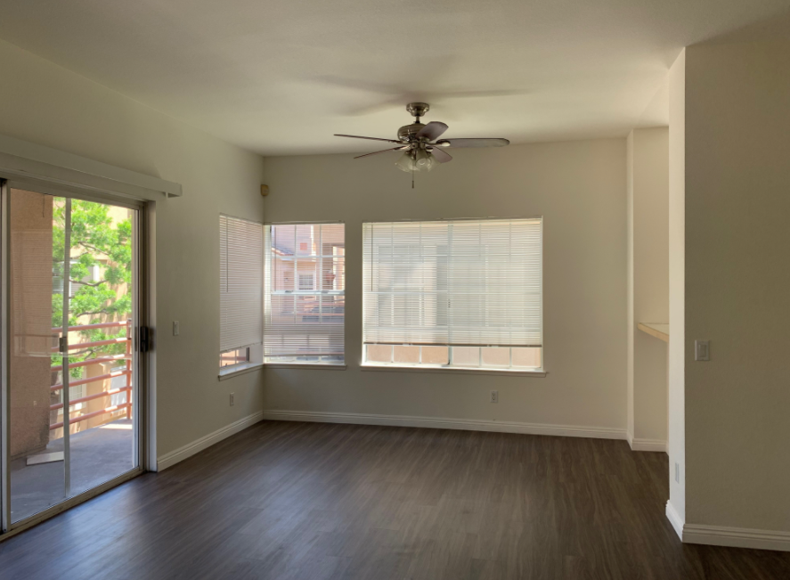 an empty living room with a ceiling fan and sliding glass doors