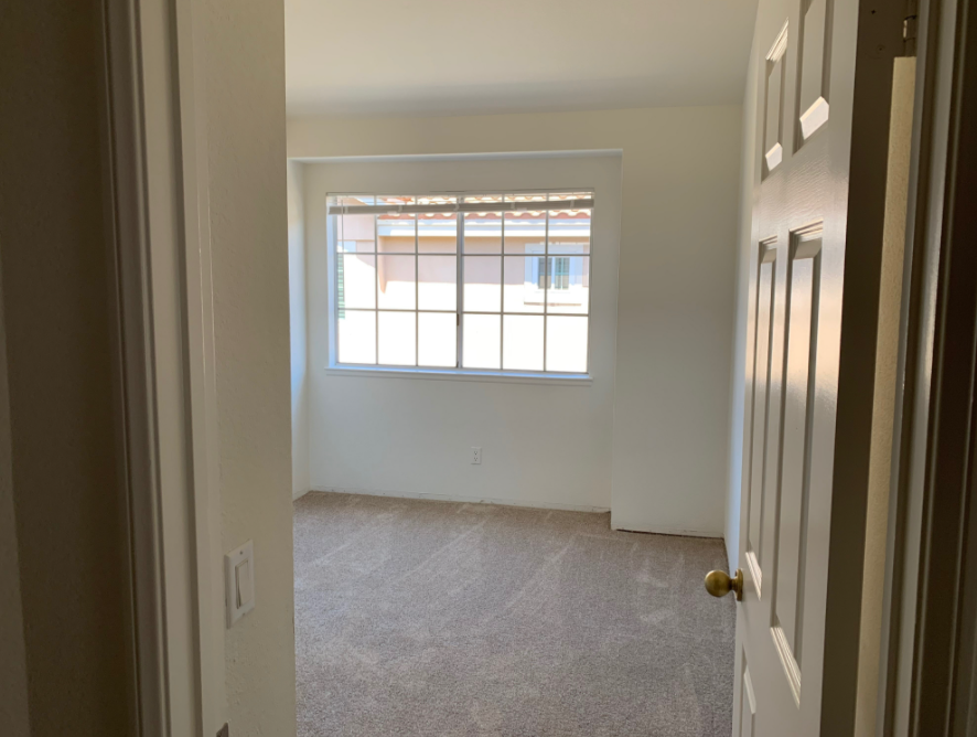 a bedroom with a large window and a carpeted floor .