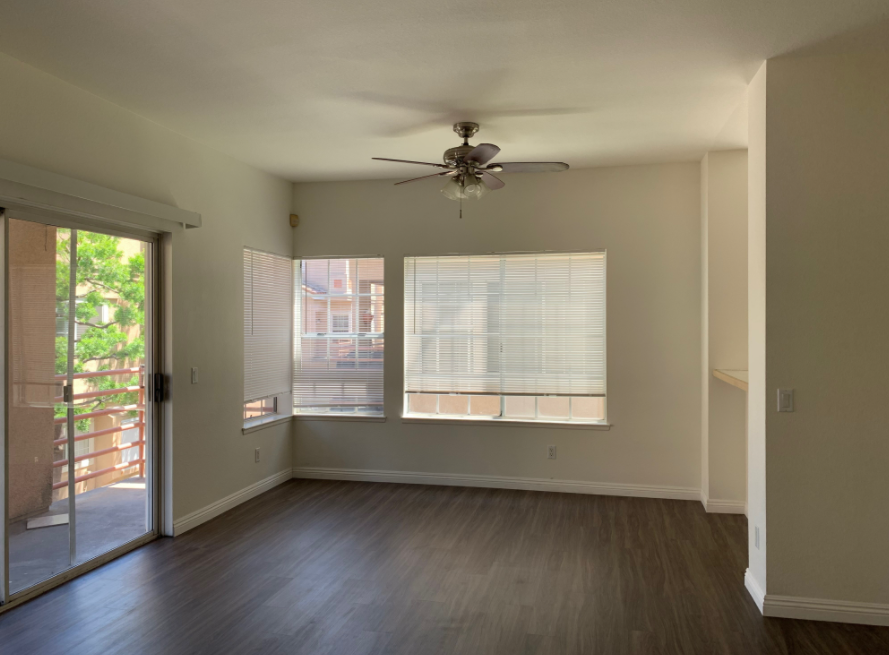 an empty living room with a ceiling fan and sliding glass doors