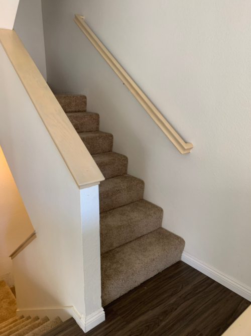 a staircase with a wooden railing and carpeted steps