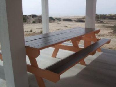 a wooden picnic table with benches under a covered porch