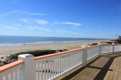 a view of the ocean from a deck with a white railing .