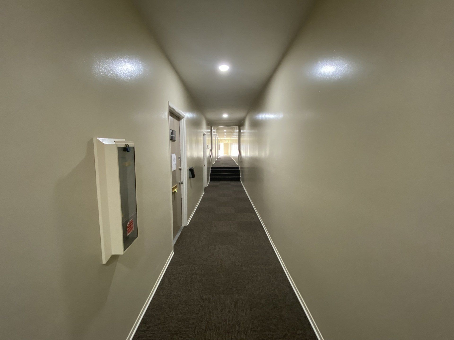 a long hallway with a fire extinguisher on the wall .