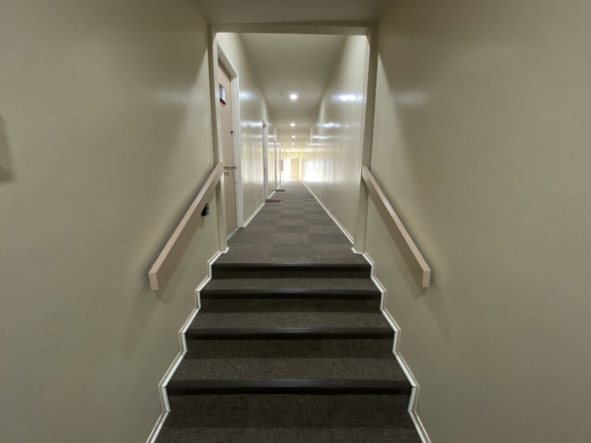 a long hallway with stairs leading up to a door .