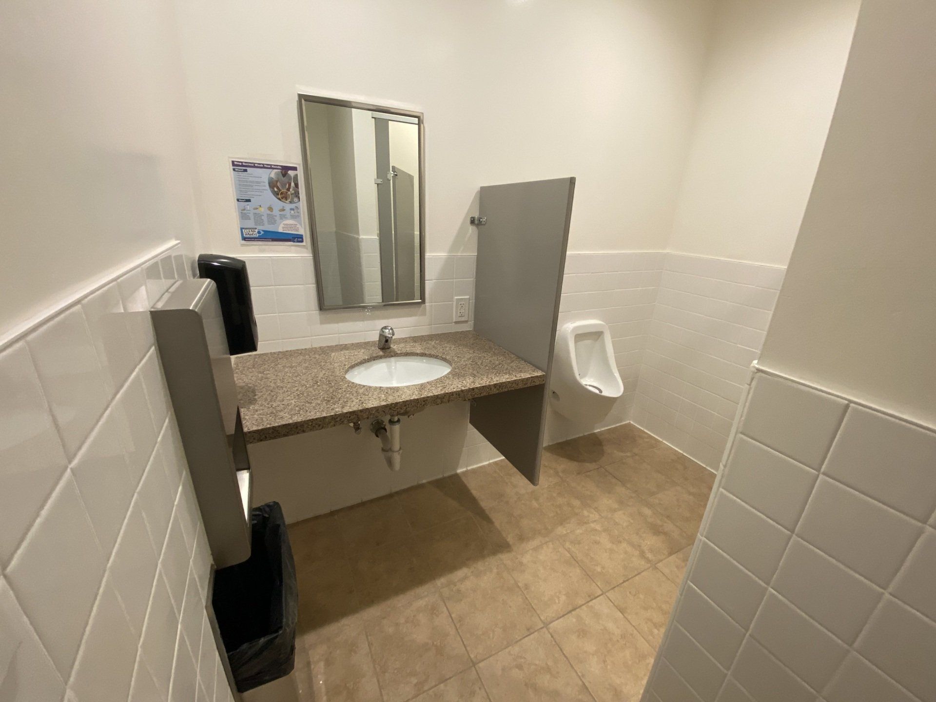 a bathroom with a sink , mirror and urinal .
