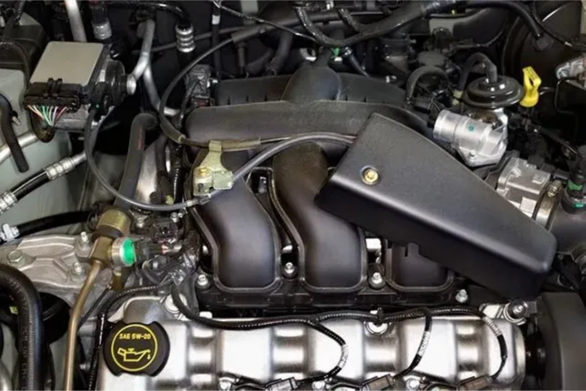 A close up of a car engine with a oil cap on it.