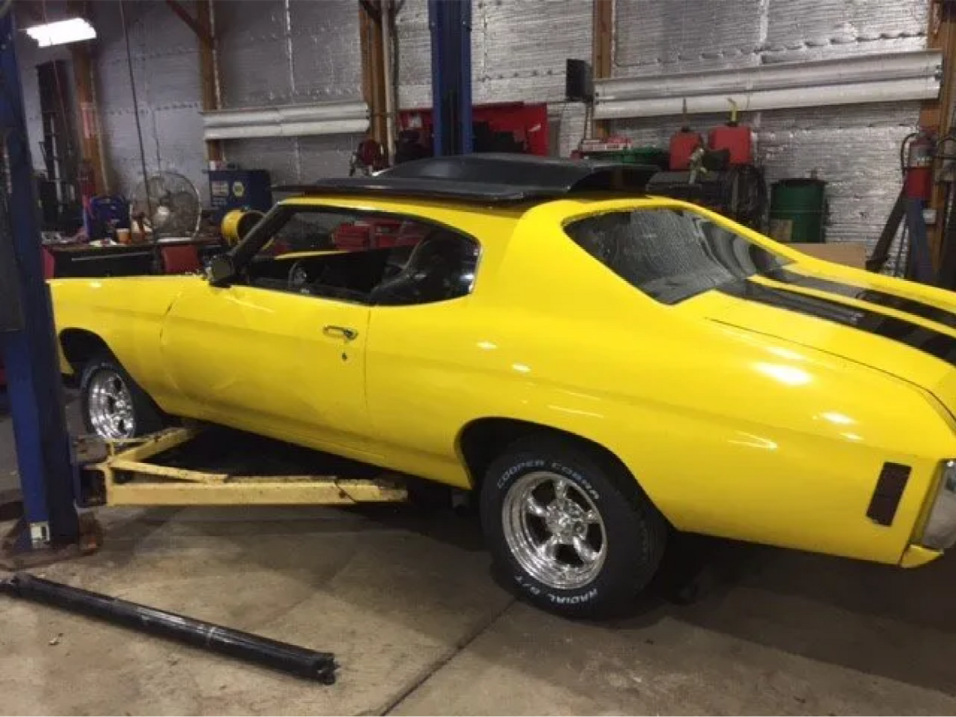 A yellow car is sitting on a lift in a garage.