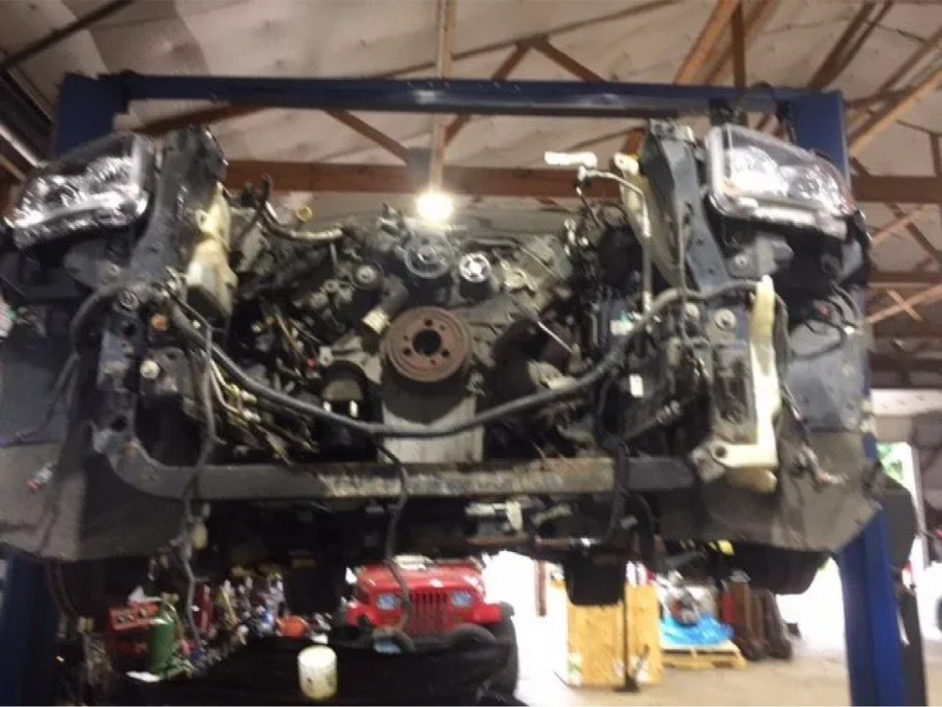 A car engine is being dismantled on a lift in a garage