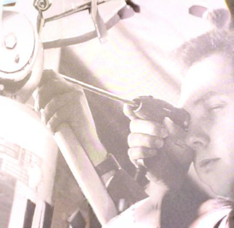 A person holds a screwdriver to a mechanical component, focusing intently on the task.