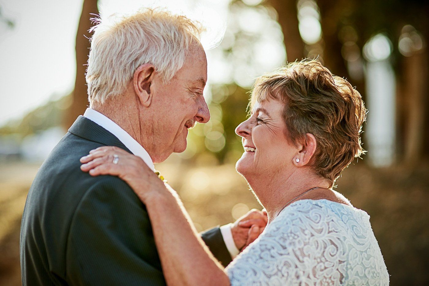 An older couple dances at their wedding while gazing into one another's eyes.
