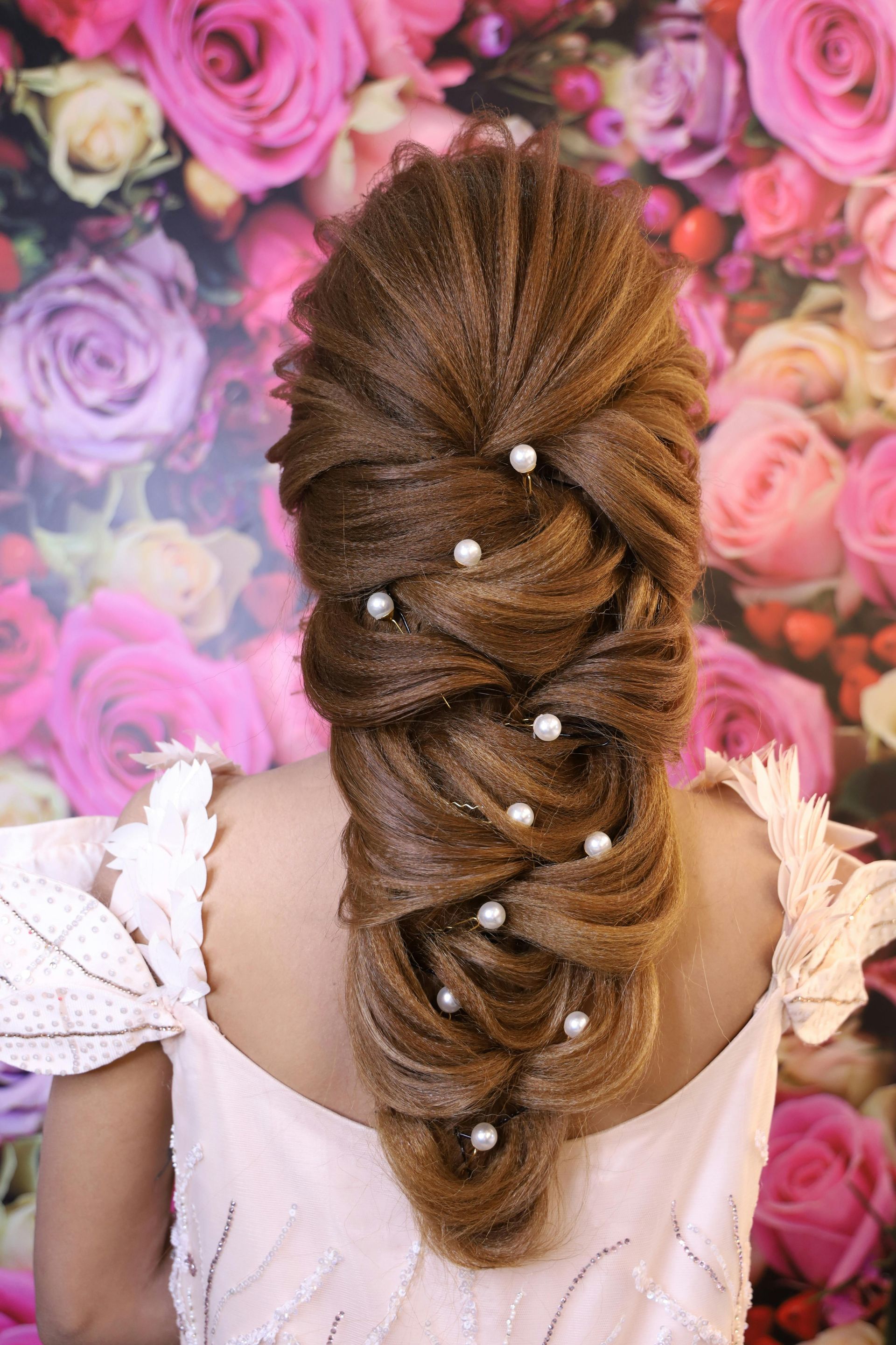 Intricately styled, crimped hair worn in a decorative, pulled-back braid adorned with small, white pearl-like beads.