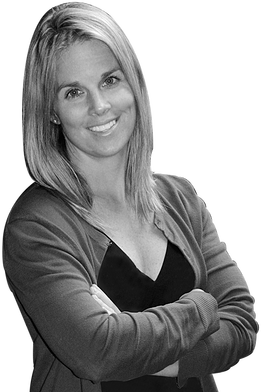 A woman with her arms crossed is smiling in a black and white photo.