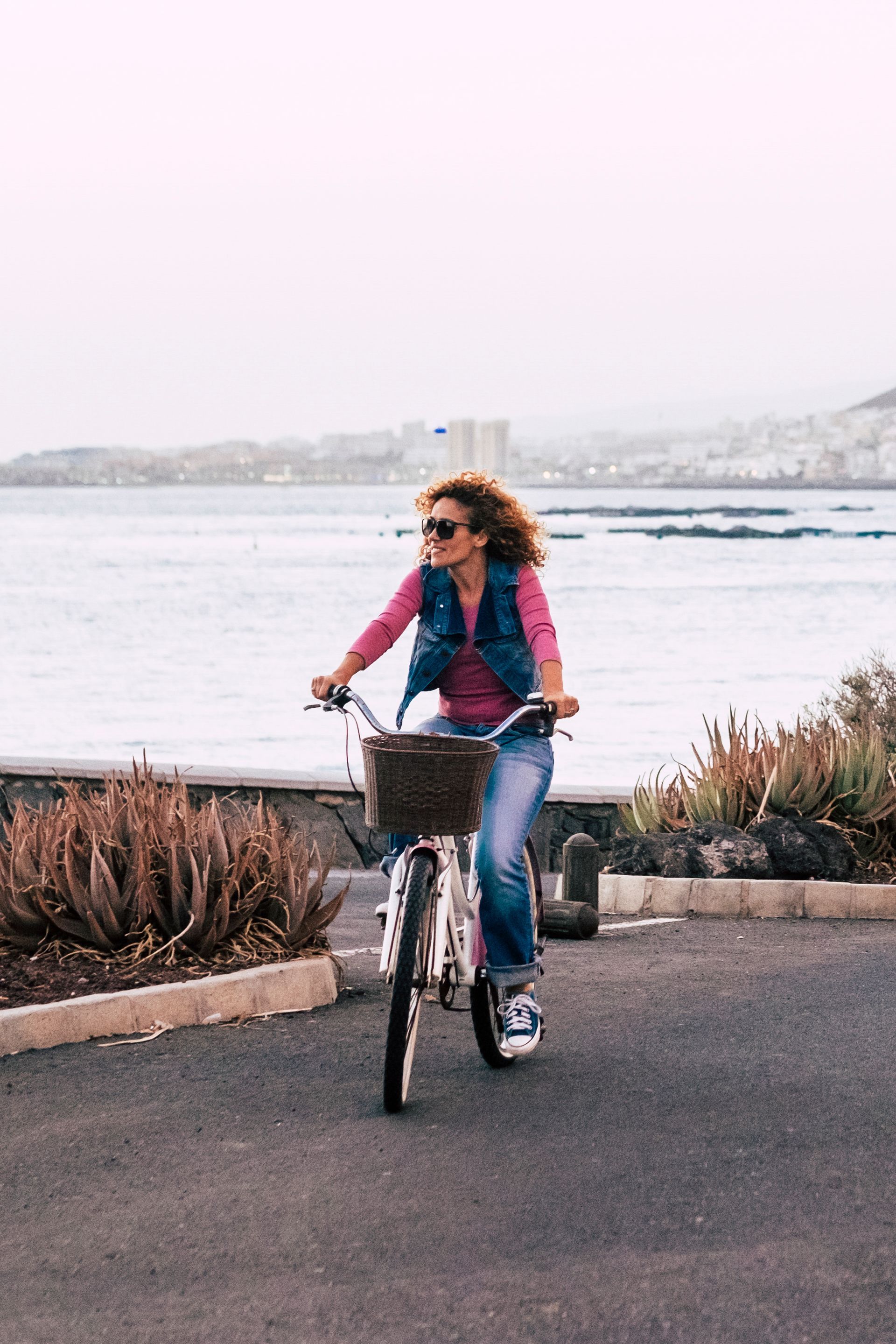 A woman is riding a bike on a road near the ocean.