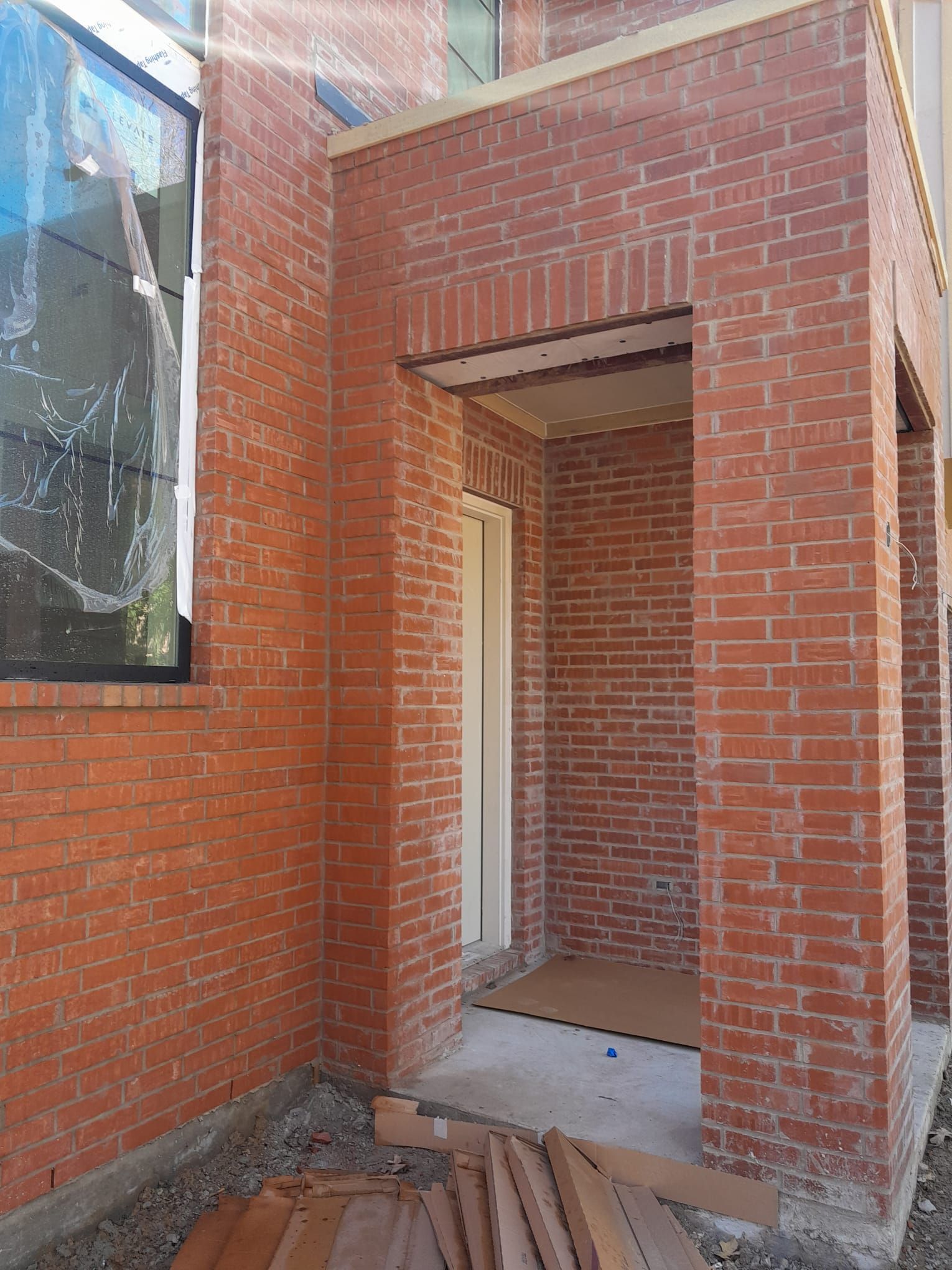 A red brick building with a white door and a window.