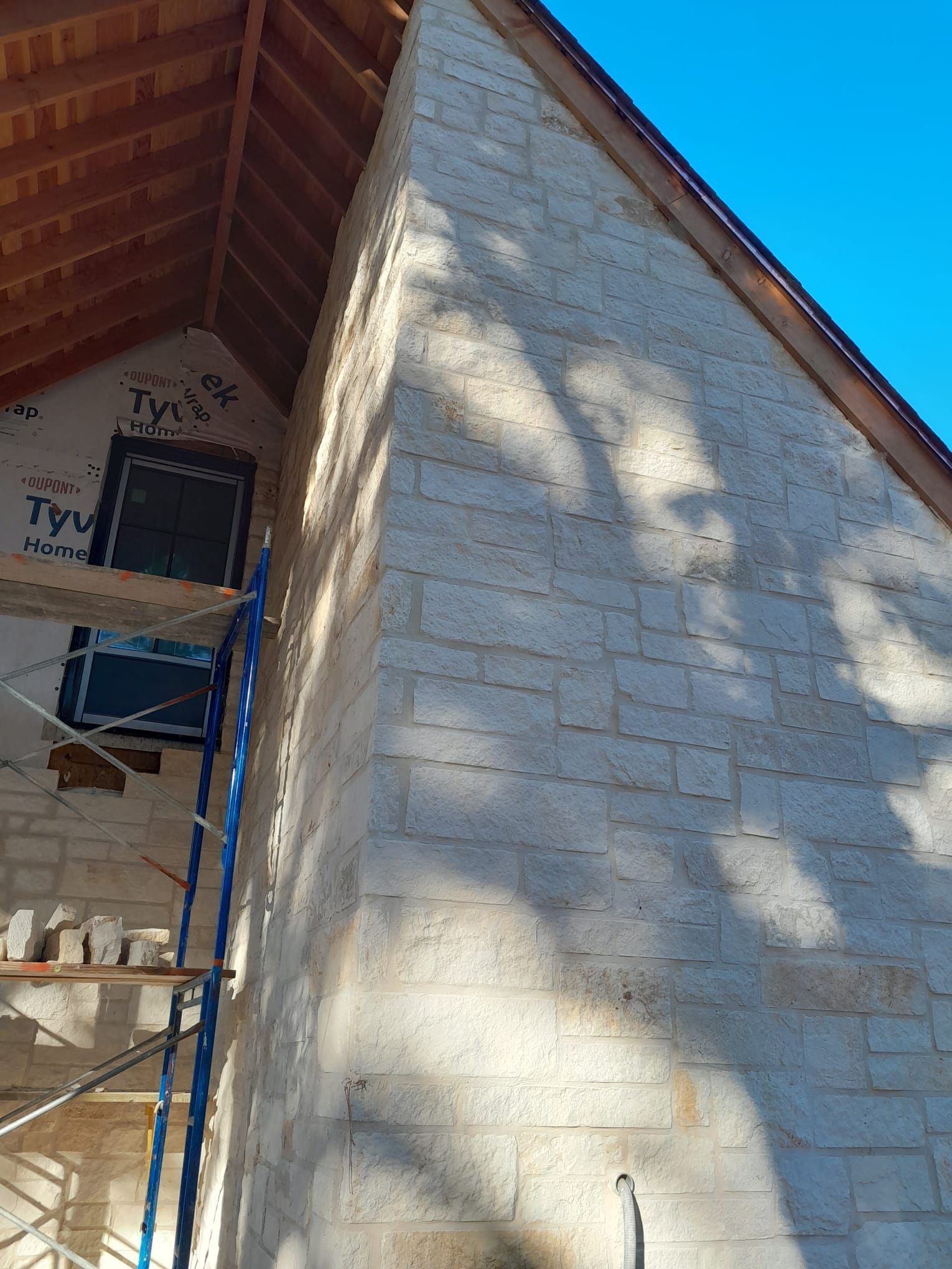 A brick building with a wooden roof is being built.
