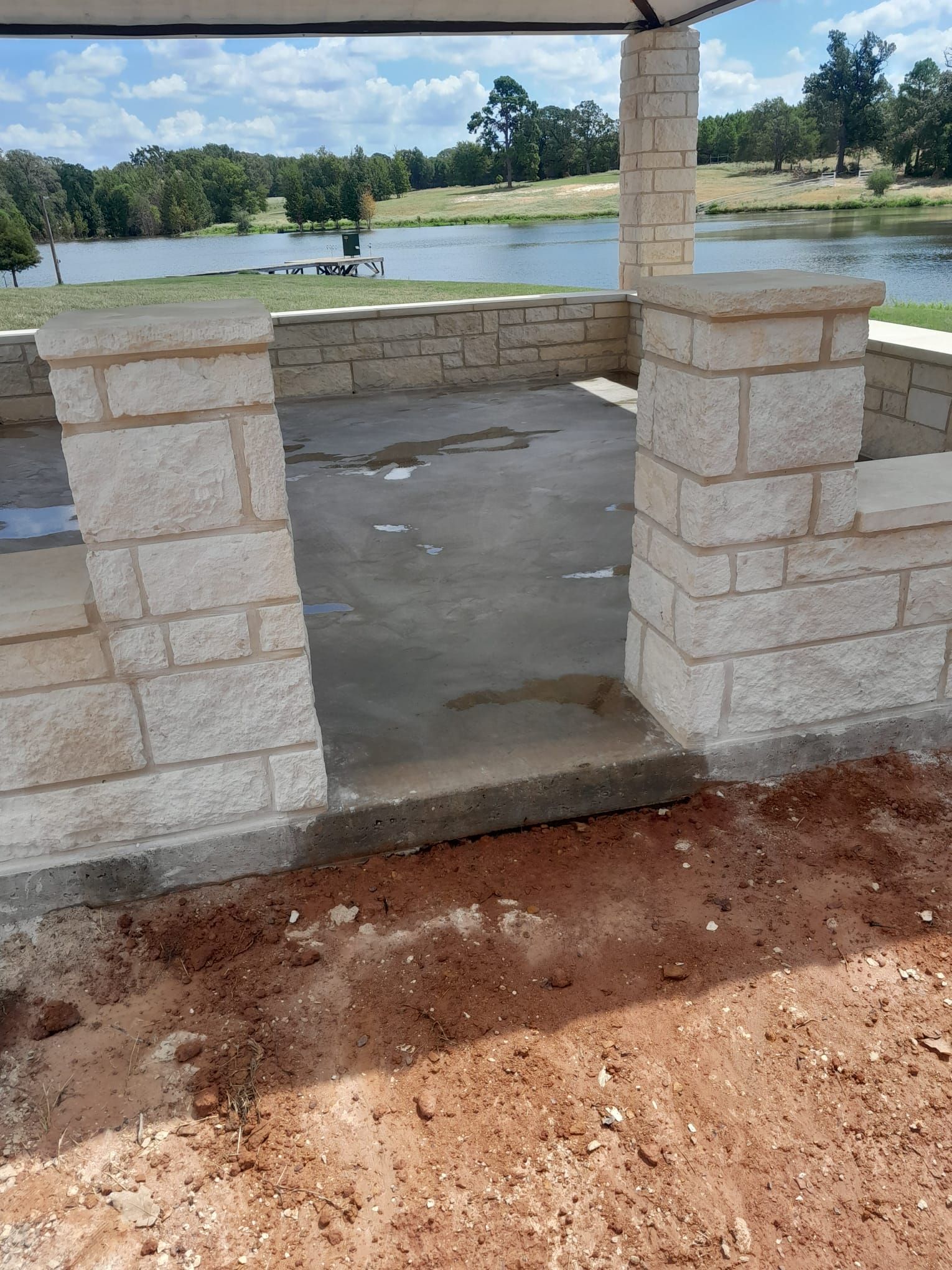 A brick wall with a view of a lake in the background