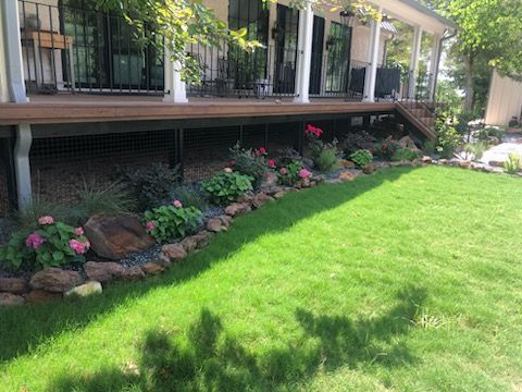 A house with a large lawn and flowers in front of it.