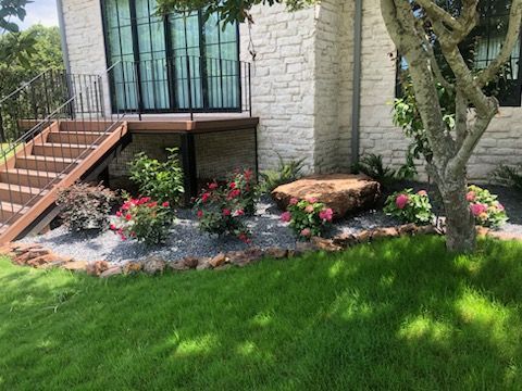 A white brick house with stairs and flowers in front of it.