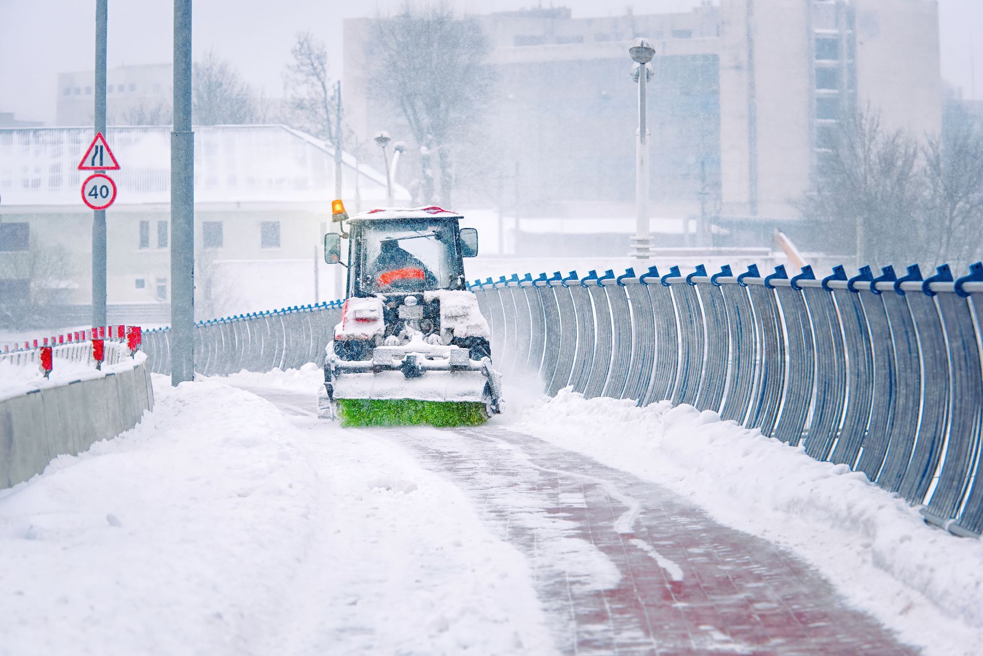 A snow blower is cleaning a snowy road.