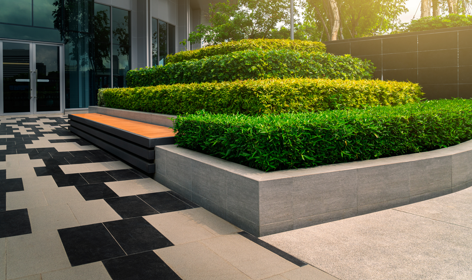 A lush green garden with a bench in front of a building.