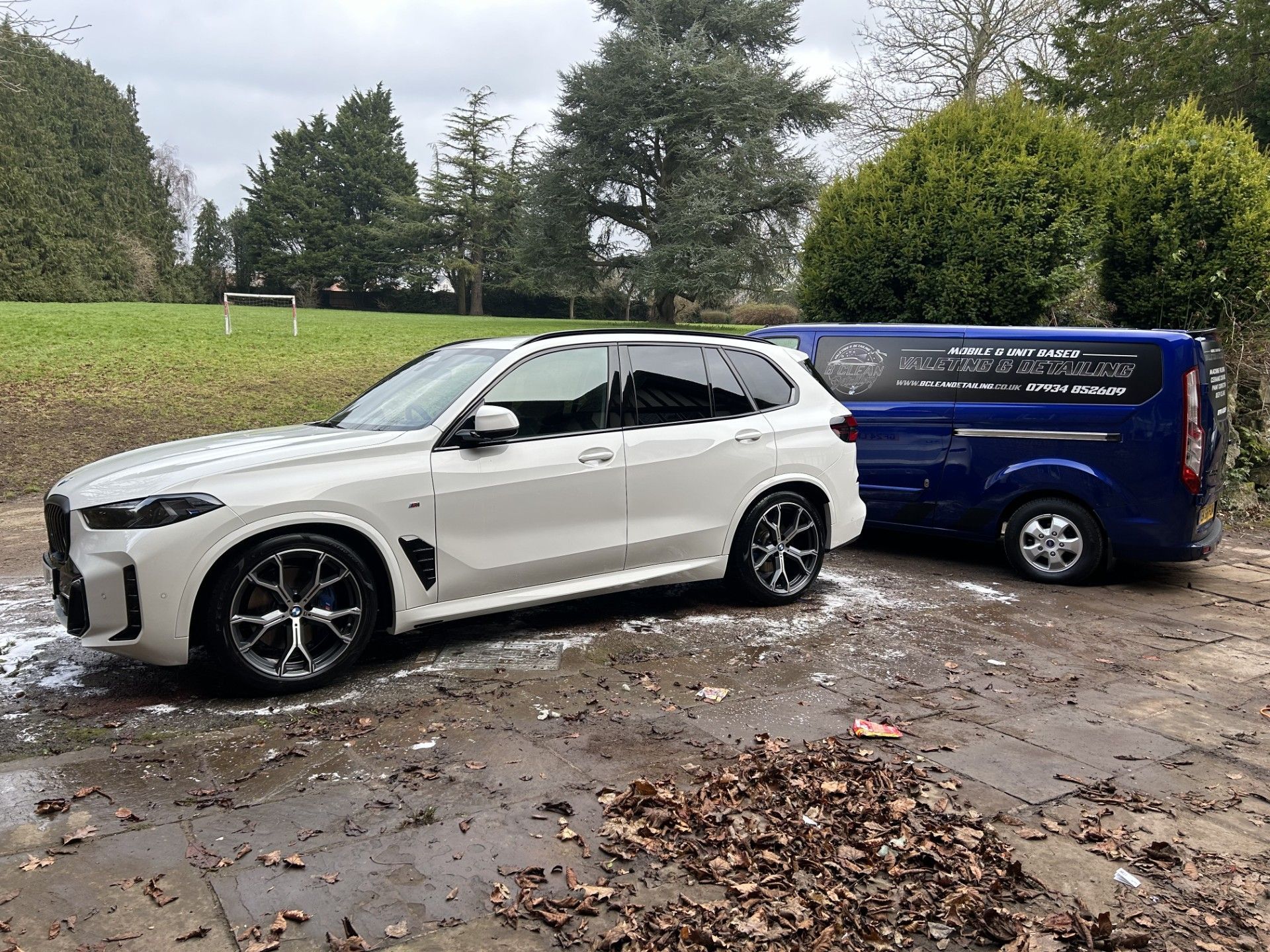 A white suv is parked next to a blue van.