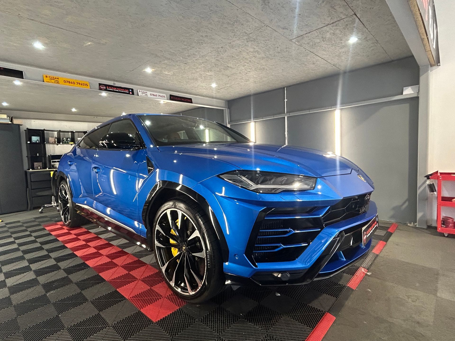 A blue lamborghini urus is parked in a garage.