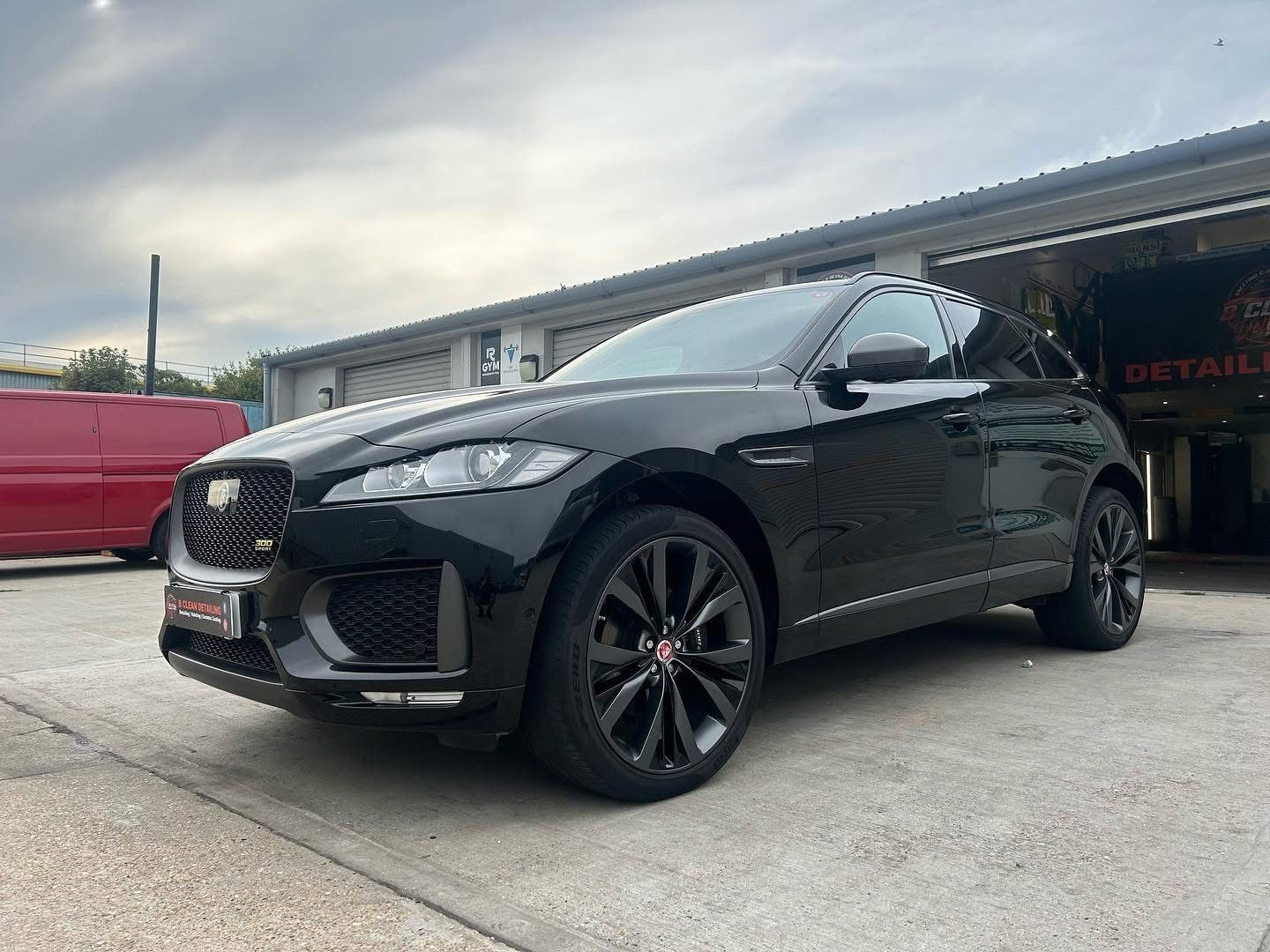 A black jaguar f pace is parked in front of a garage.