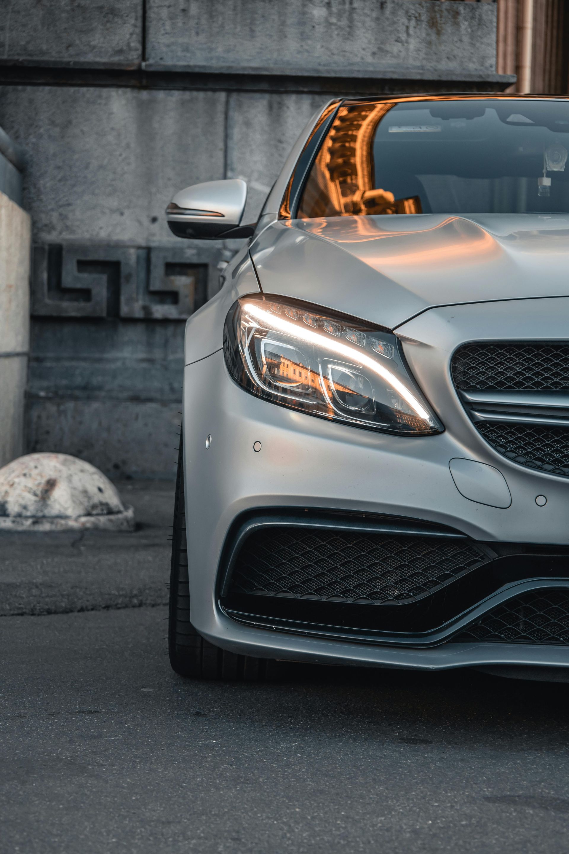 A silver mercedes benz c63 amg is parked in front of a building.