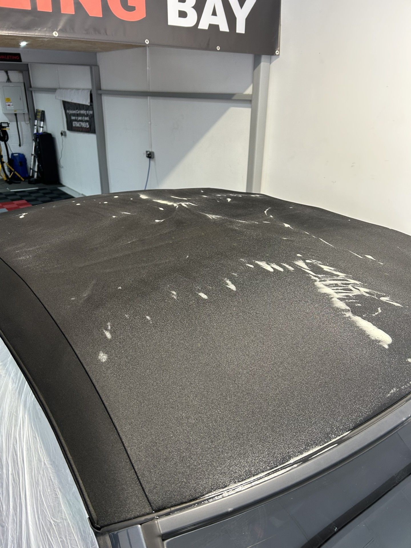 A blue sports car is parked in front of a garage.