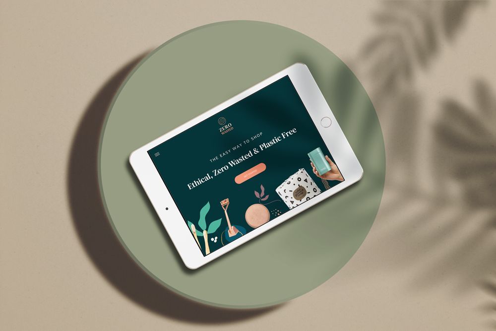 Tablet displaying the Zero Wasted website on a green backdrop, with plant and food illustrations.