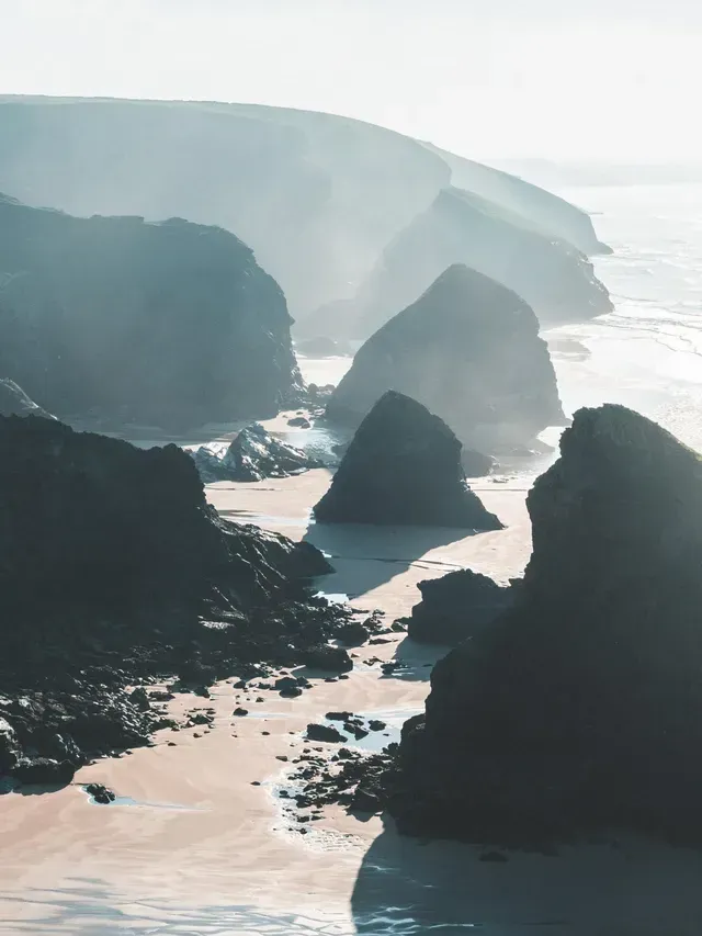 Rocky coastline with cliffs and sea stacks, bathed in sunlight.