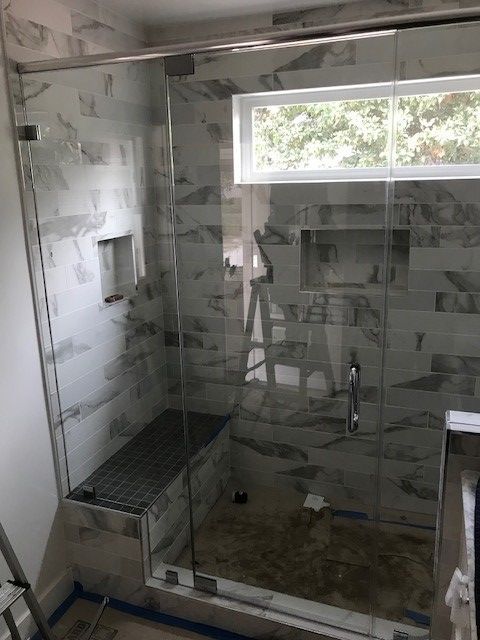 A bathroom with a sliding glass shower door and a window.