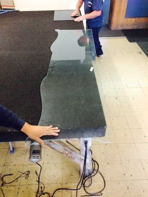 A person is cutting a piece of glass on a table