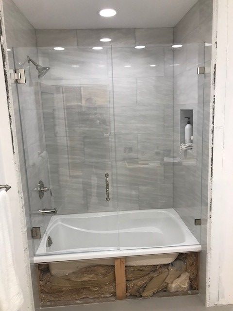 A bathroom with a bathtub and a shower with a glass door.