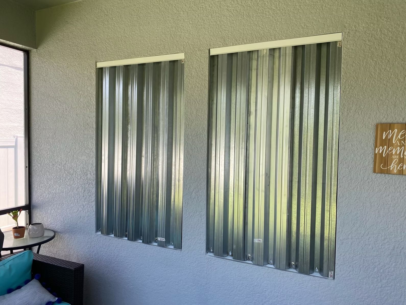Two corrugated metal curtains hung on a stucco wall; patio setting.