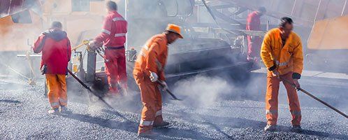 Construction workers smoothing out asphalt on roadway Construction workers smoothing out asphalt on roadway