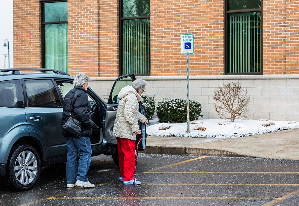 elderly woman and helper walking on icy parking lot