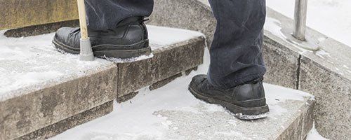Person wearing black shoes walking up snowy stairs