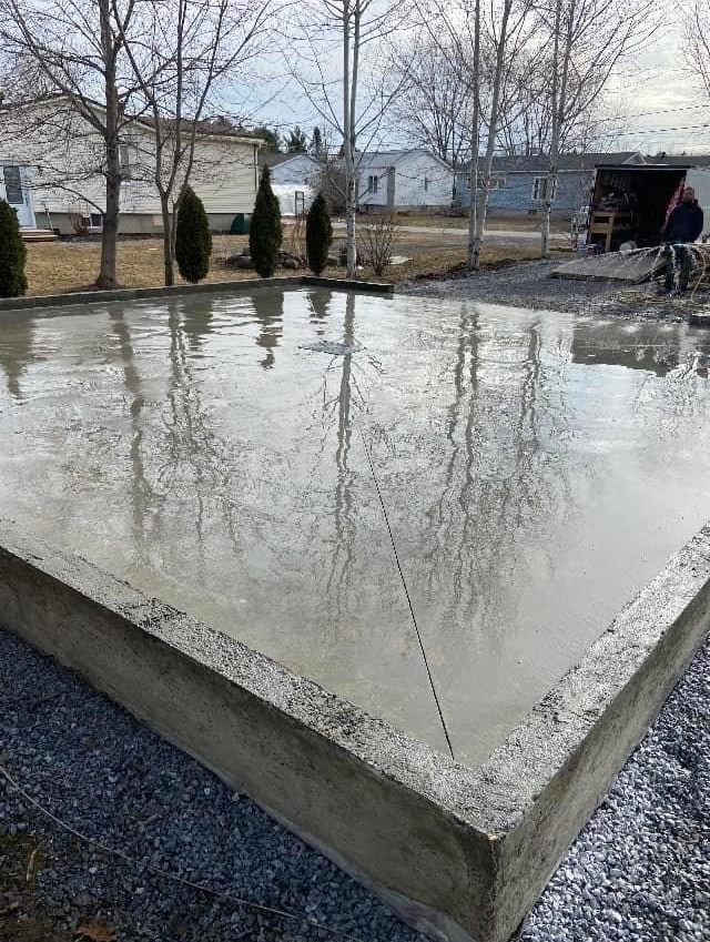 Une grande dalle de béton repose sur du gravier dans une cour.