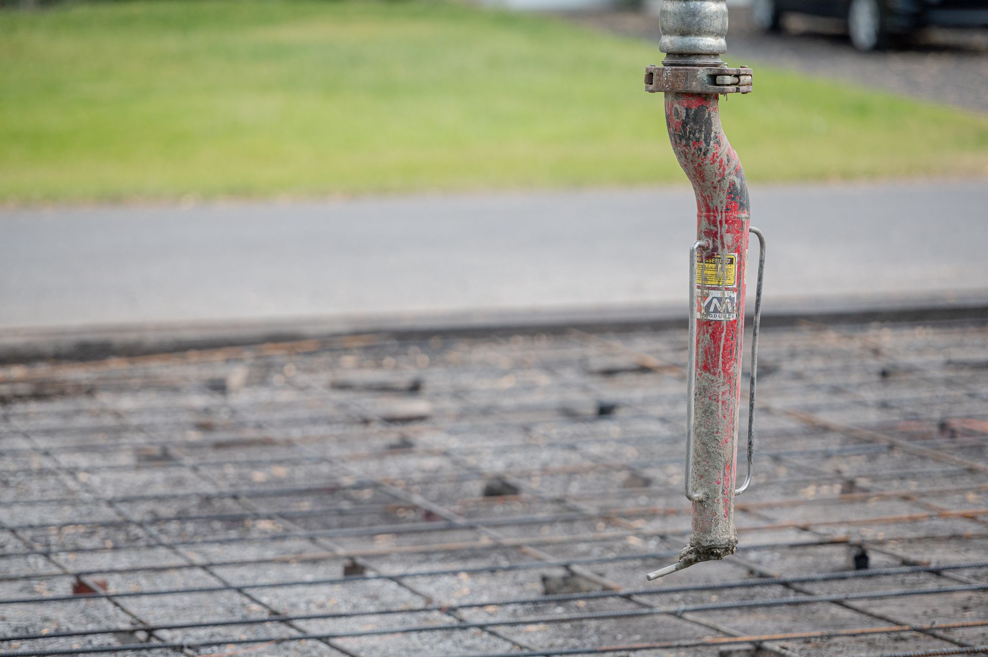 Un tuyau rouge est posé sur un sol en béton.