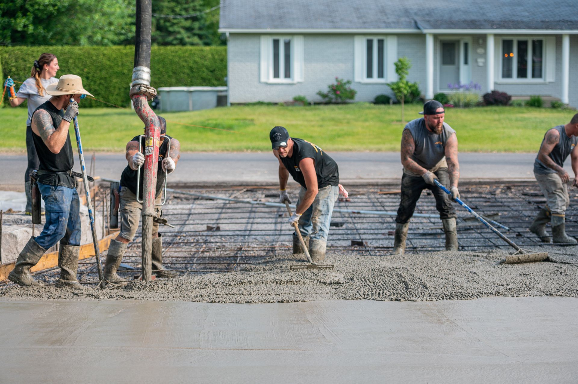 Un groupe d'ouvriers du bâtiment travaille sur une allée en béton devant une maison.