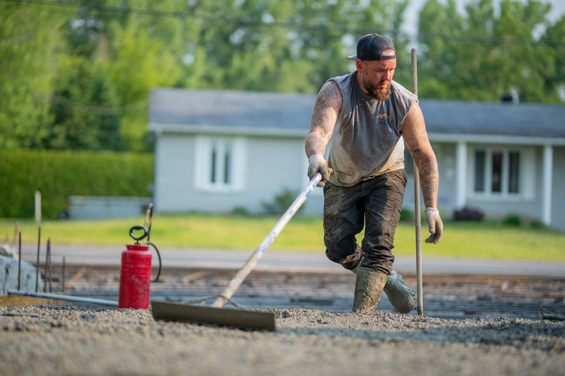 Un homme travaille sur une allée en béton avec un râteau.