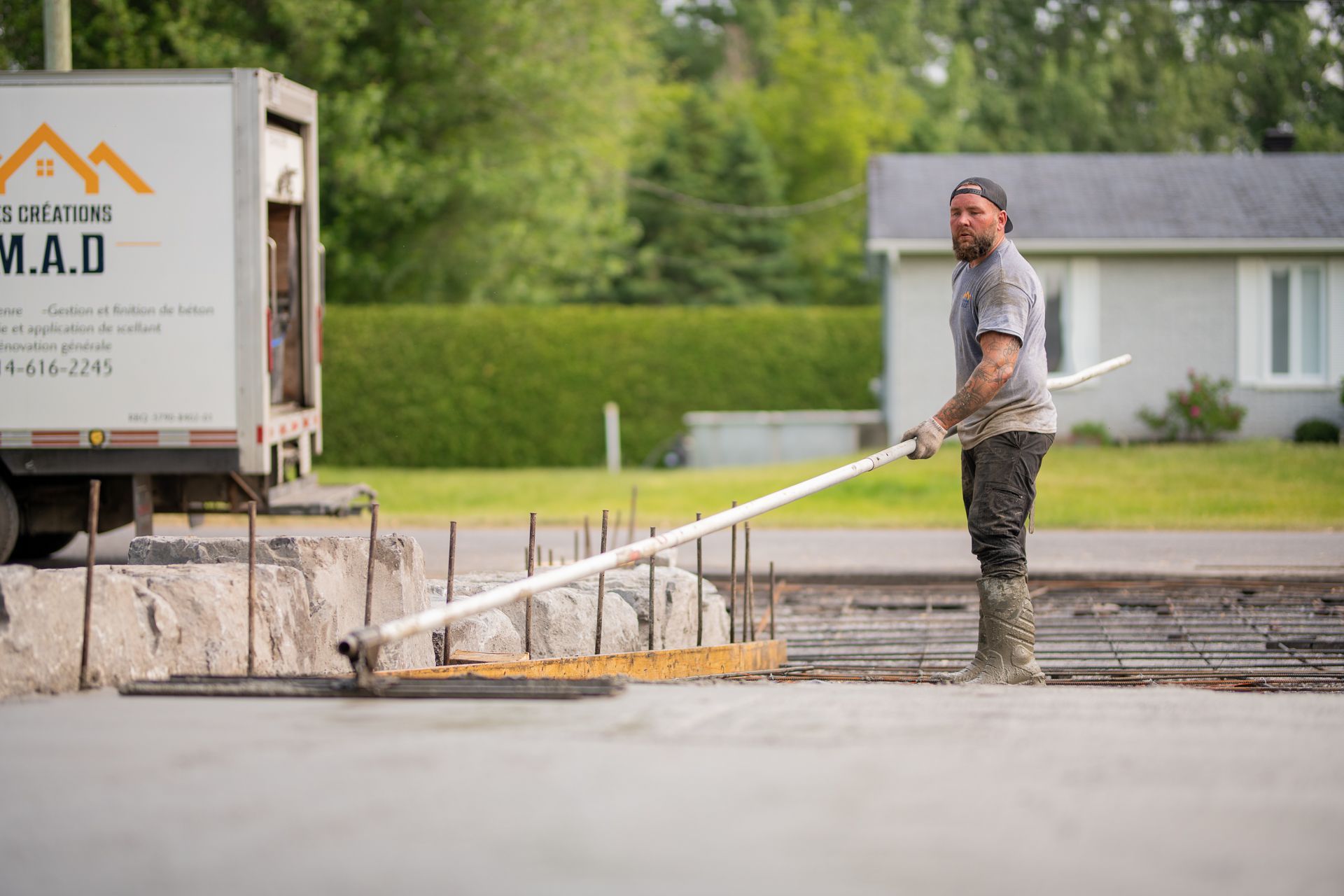 Un homme étale du béton dans une allée avec une truelle.