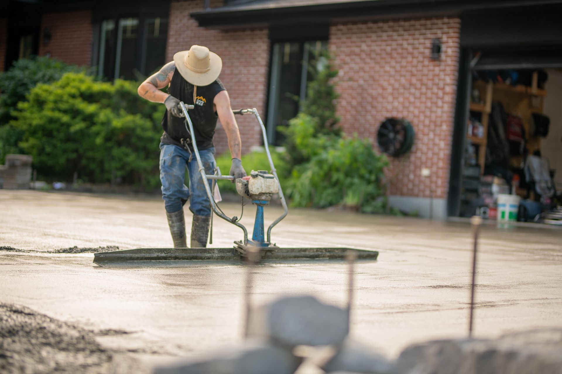 Un homme utilise une machine pour niveler une allée en béton.