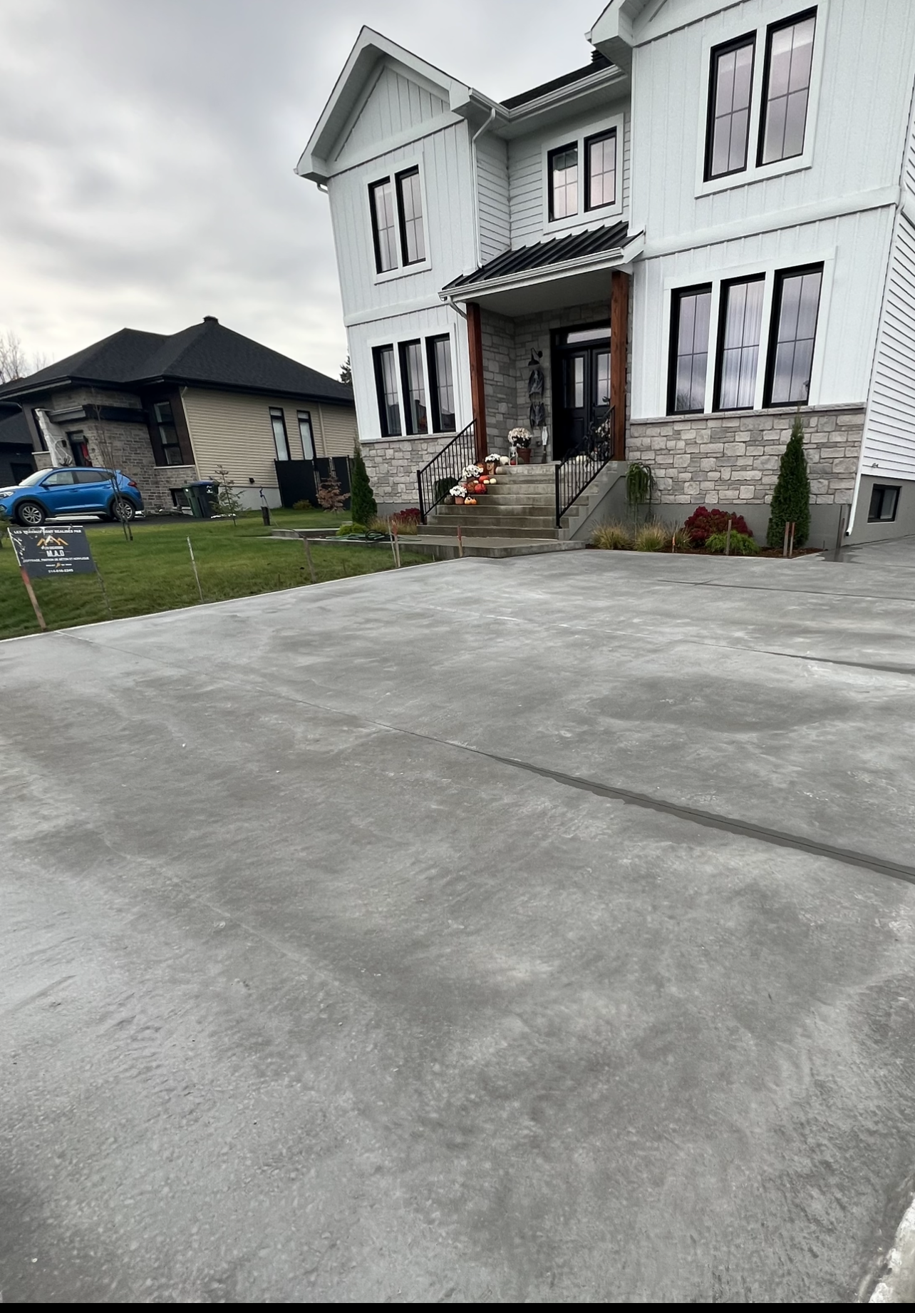 Une grande maison blanche avec une allée en béton devant.