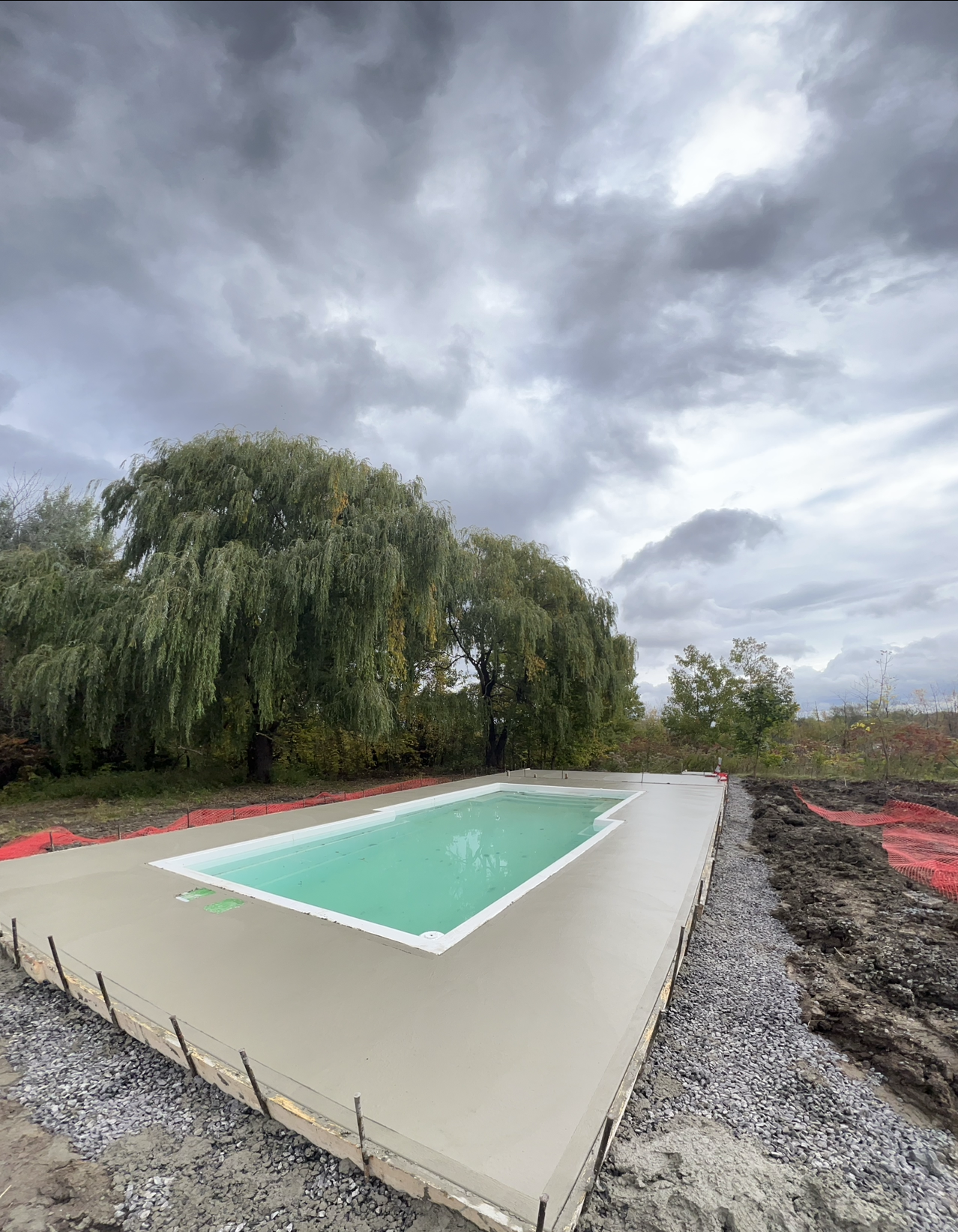 Une grande piscine est en cours de construction au milieu d'un champ de terre.