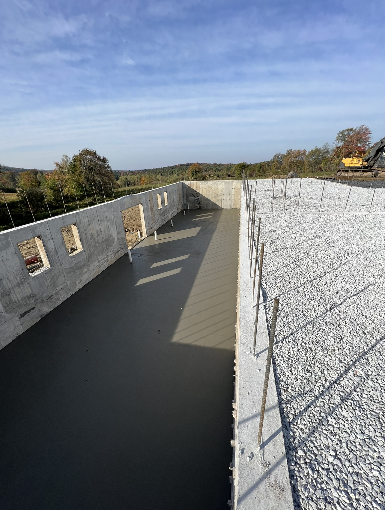 Un mur de béton est en construction à côté d'un tas de gravier.