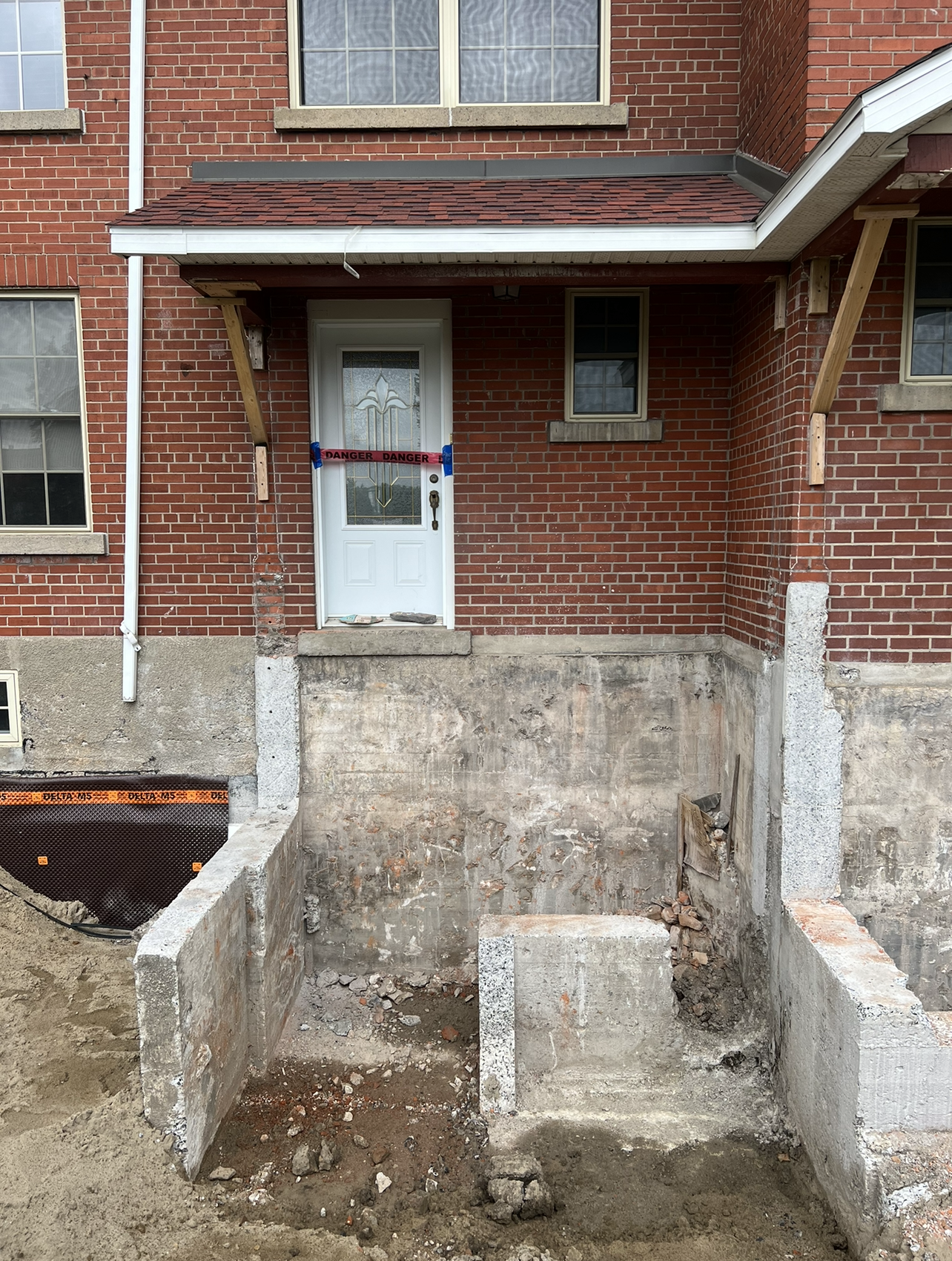Un bâtiment en brique avec une porte blanche et des marches en béton